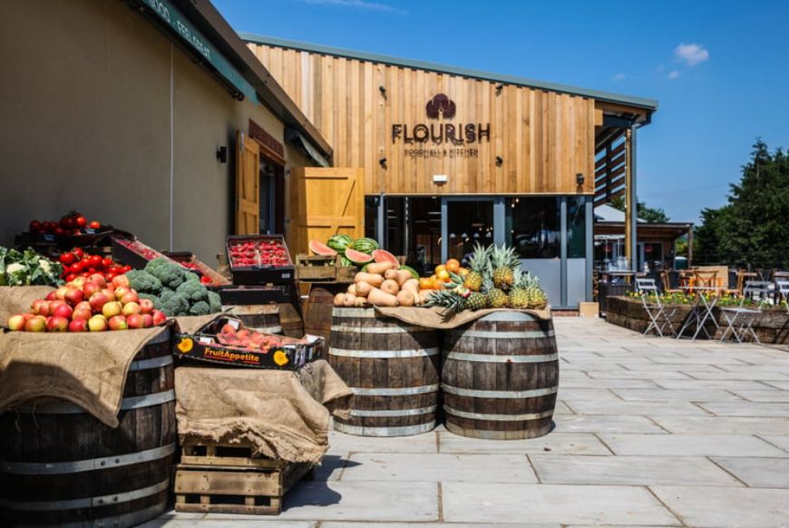 the outside of a farm shop with barrels of fruit and veg